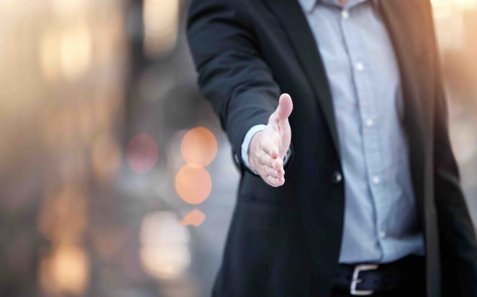 Cropped shot of an unrecognisable businessman standing in the city with his hand outstretched.